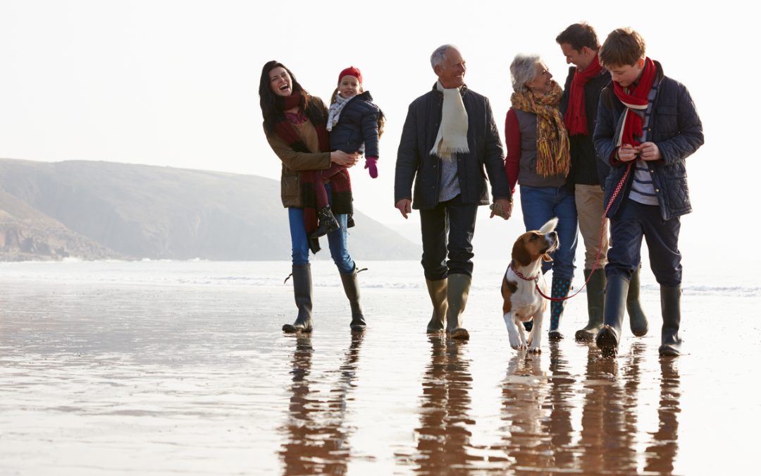 A multi-generation family walking together on a beach.