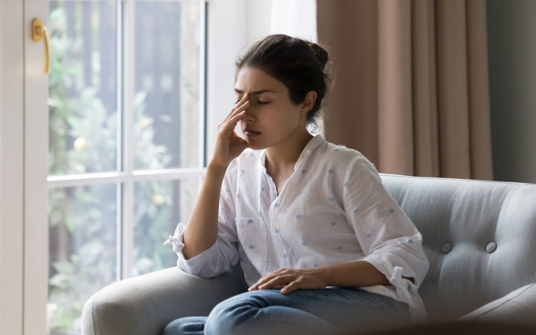 A young woman looking stressed at home.
