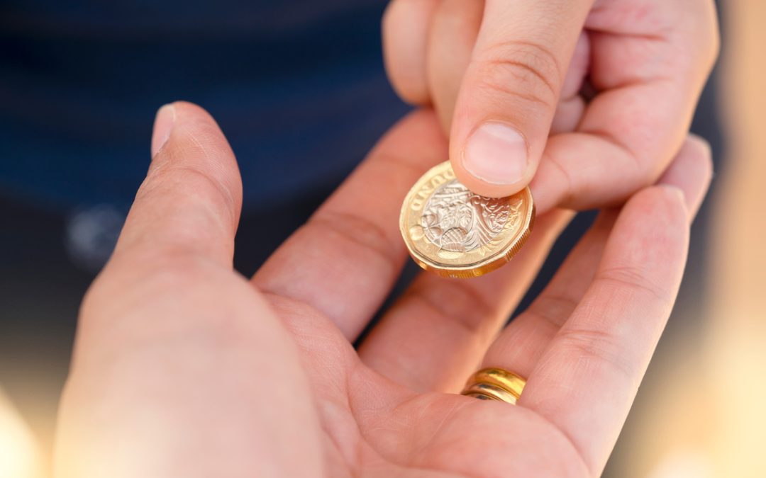 Someone passing a £1 coin to another person.