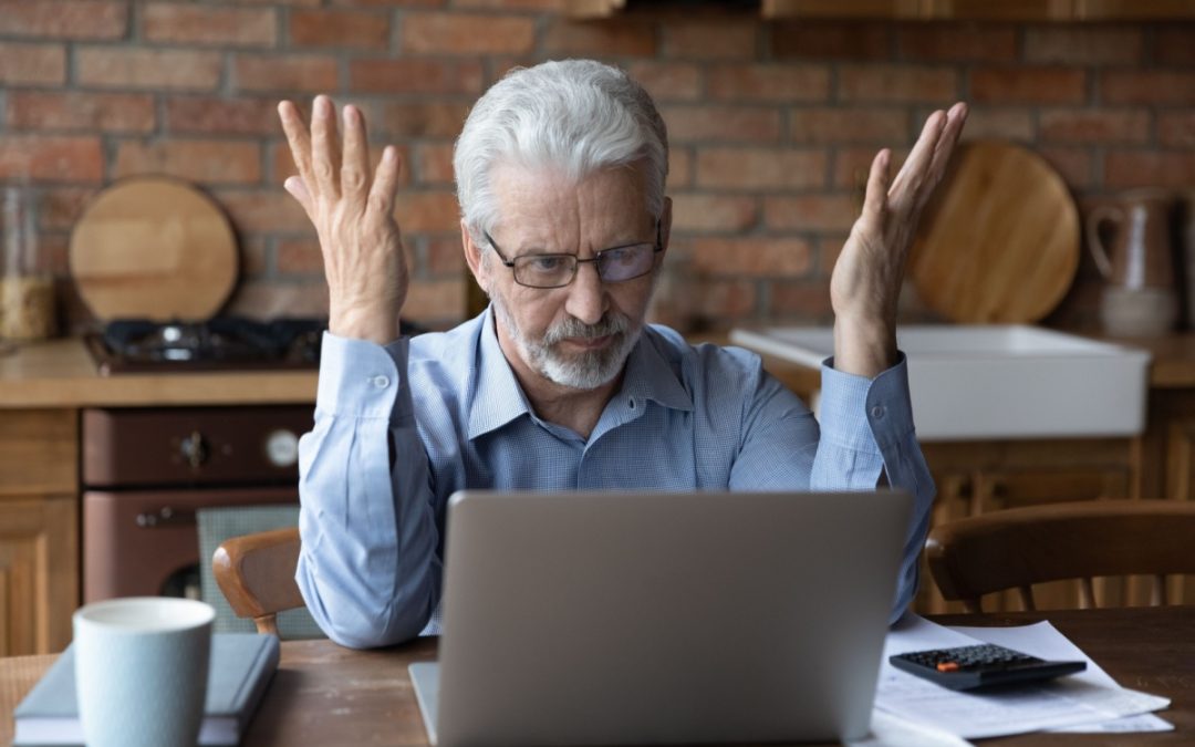 An older man frustrated, sitting at his laptop