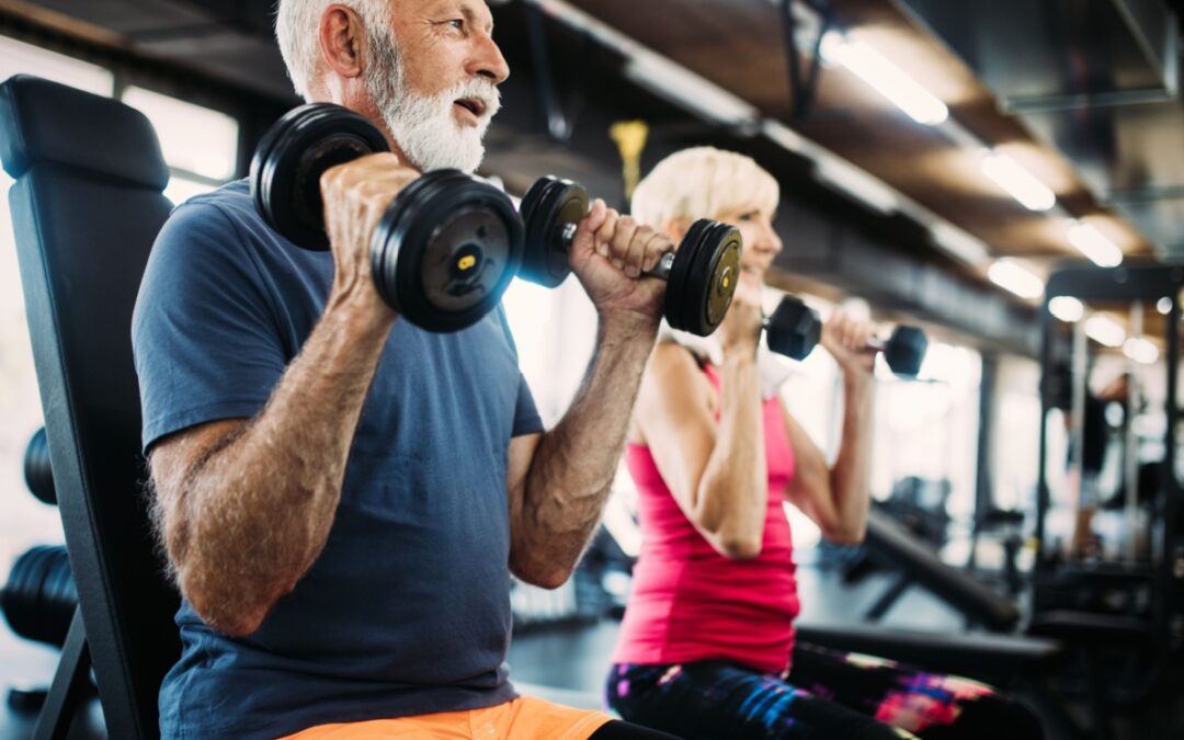 Two people in their 60s using weights in a gym.