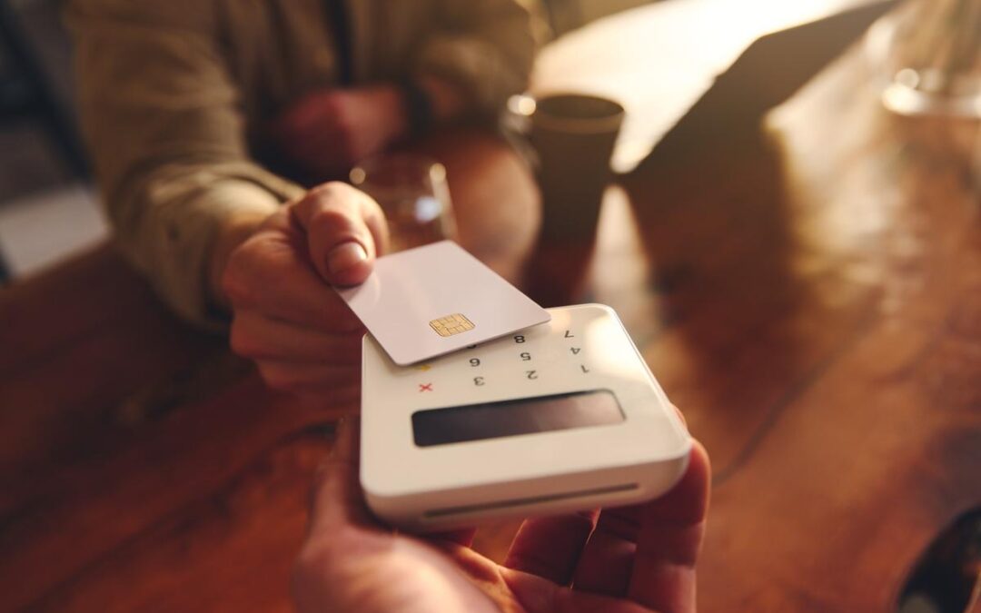 A person using their debit card to pay in a café.