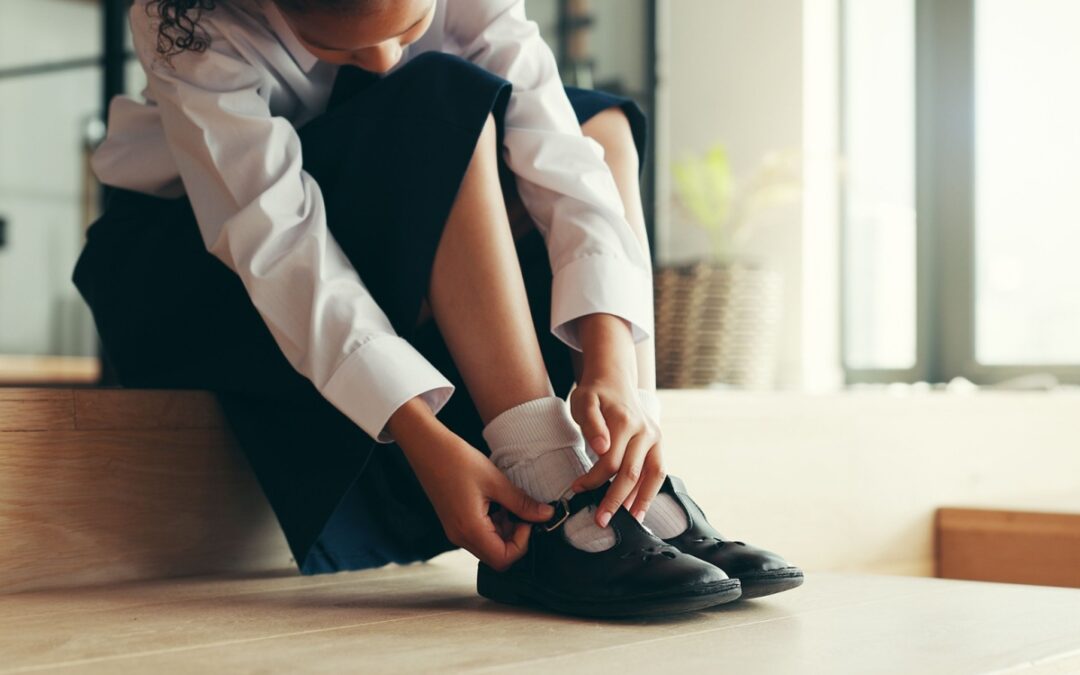 A girl putting on school shoes.