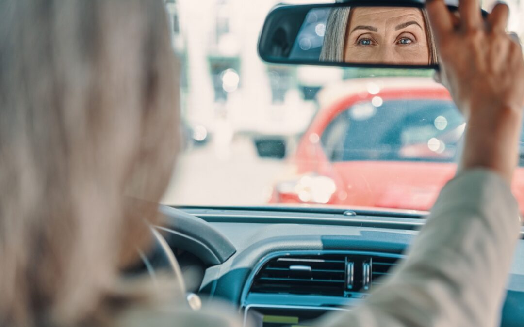 A driver adjusting the rear view mirror in a car.